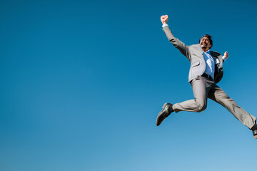 Obraz premium A man in a suit jumps energetically in the air, showcasing energy and excitement.