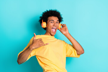 Portrait of carefree man with afro hair wear oversize t-shirt touch headphones show shaka symbol...