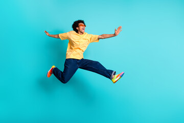 Full length photo of positive guy dressed yellow t-shirt sunglass run look at offer empty space isolated on turquoise color background - obrazy, fototapety, plakaty