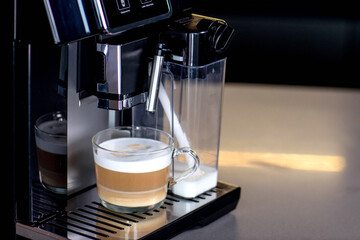 Modern coffee machine with glass cup of latte in kitchen