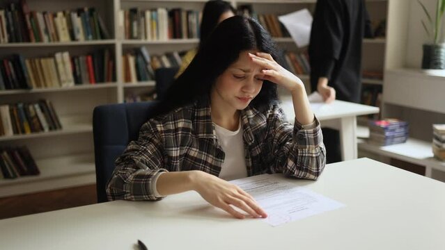 Portrait of upset young asian student got a bad grade on the exam while her group mate happy with high mark at classroom Stressed girl failed exam at university Opposite emotions