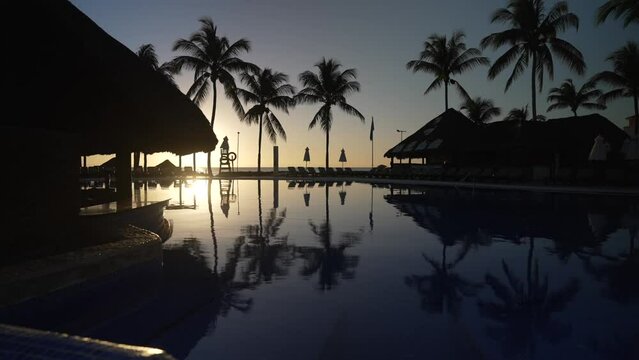 View of palm trees reflected in pool, sunshades and sea at sunrise near Puerto Morelos, Caribbean Coast, Yucatan Peninsula, Mexico, North America