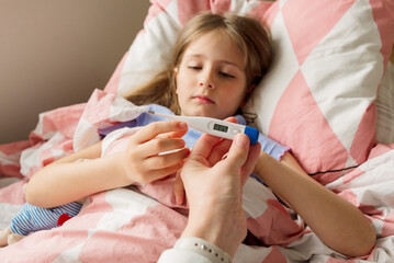 young mother using a thermometer to temperature with her little daughter