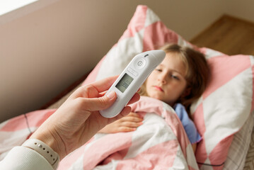 woman taking care of her daughter`s temperature at home