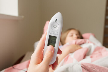 woman checking temperature of thermometer in bedroom