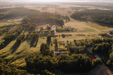Valmiera, Latvia - August 12, 2023 - Sunlit aerial view of a 9-hole golf course with a driving...