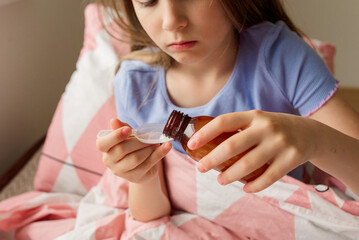 sick girl pours herself some medicine into the spoon