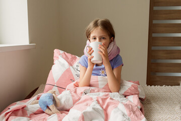 girl in pajamas and mask in bed with a cup of tea.