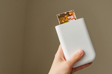 girl holding a white portable photo printer