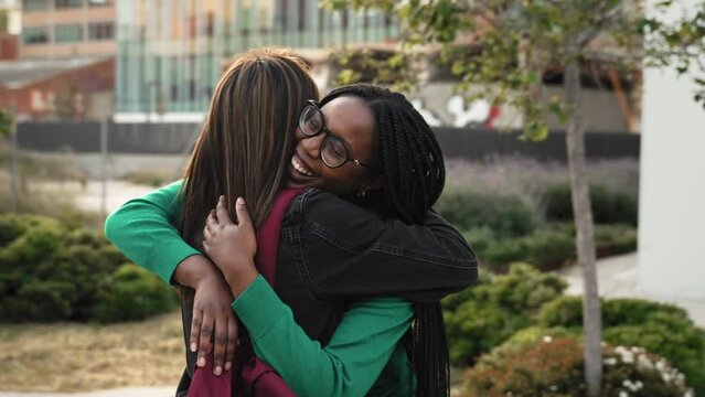 African woman embracing girl with love and emotion - Two happy female best friends hugging each other