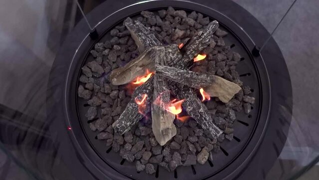A bio-ethanol fireplace burns with orange flames in a dark room