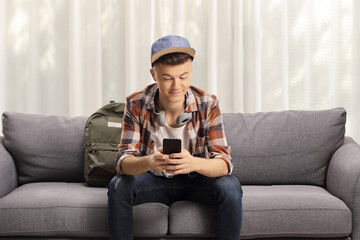 Male teen student sitting on a sofa with headphones