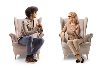 Young man sitting in an armchair and talking to a middle aged woman