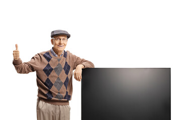 Elderly man leaning on a flat lcd tv screen and gesturing thumbs up
