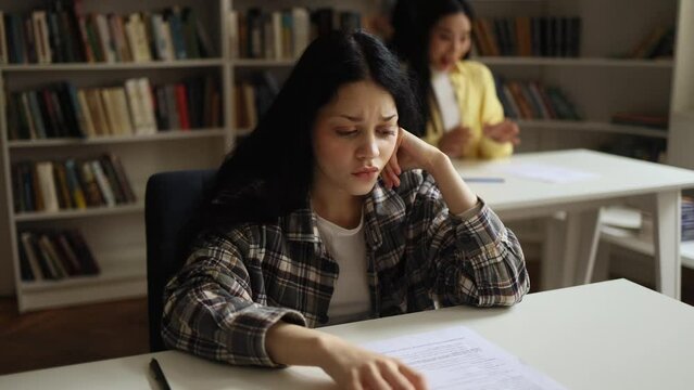 Portrait of upset young asian student got a bad grade on the exam while her group mate happy with high mark at classroom Stressed girl failed exam at university Opposite emotions