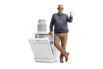 Mature man with a dishwasher and a pile of clean plates gesturing thumbs up