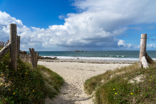 Un chemin serpentant à travers les dunes guide les visiteurs vers la plage, offrant une vue pittoresque sur les paysages côtiers de la Bretagne.