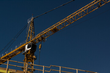 Construction crane yellow at urban high rise construction site on sunny day