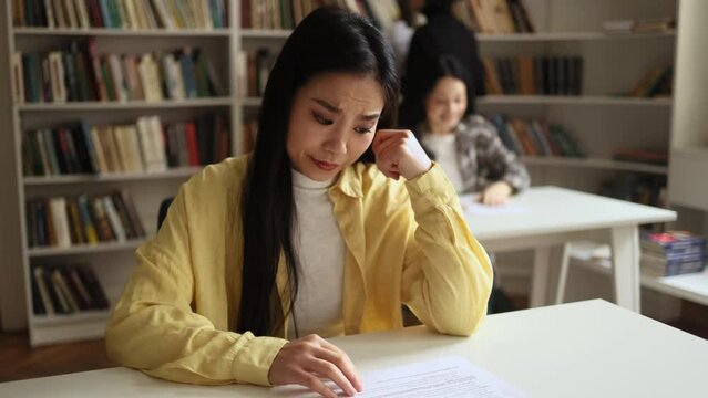Portrait of upset young student got a bad grade on the exam while her group mate happy with high mark at classroom Stressed girl failed exam at university Opposite emotions