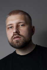 Portraits of a Millennial guy with a short haircut and beard, earrings in his ears