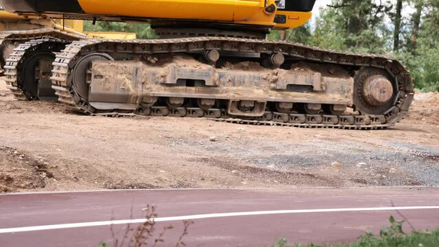 Large tracked vehicles. Road construction equipment. Close-up of one of the tracks of a road tractor. Yellow cabin of crawler equipment standing motionless.