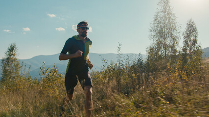 Athletic Caucasian man male guy sportswear sunglasses runner hiker running valley hiking run moving...