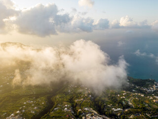 Aerial view at dawn from Mount Epomeo in Ischia. Flight in the clouds with a sea view