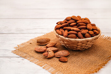 Almonds in Wicker Basket Bowl on White Wooden Table. Almond Concept with Copy Space