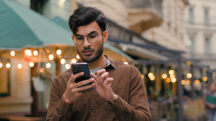 Nervous lonely Indian Arabian ethnic male businessman guy looking around feeling lost. Man holding...