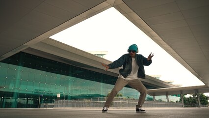 Motion shot of happy hipster practice b boy dance with stylish cloth at building. Dancer enjoy show...