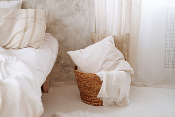 A basket full of pillows and a blanket is sitting on the floor in front of a white wall