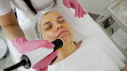 Beautiful young woman in a beauty clinic. A cosmetologist does a hydro facial procedure on a...
