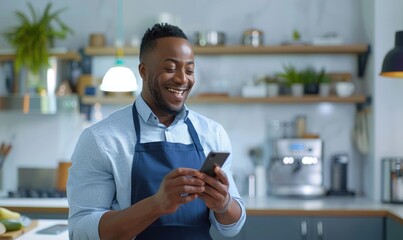 A handsome smiling man holding a cell phone in his hand standing in his kitchen
