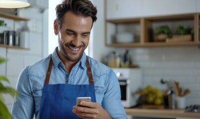 A handsome smiling man holding a cell phone in his hand standing in his kitchen