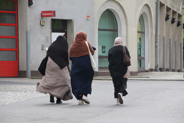 drei muslimische frauen spazieren über eine straße in neukölln