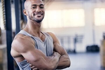 Man, portrait and arms folded in gym for workout with smile, training or exercise for fitness. Male...