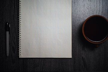 Workplace. Notebook with black marker and coffee mug on wooden table