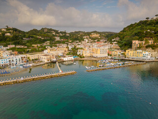 Fototapeta premium Vista aerea dell'alba del porto di Lacco Ameno ad Ischia. Roccia, mare, sole e mille colori
