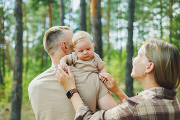 A walk of dad and mom with a baby in the park. A happy family couple with a small newborn baby in...