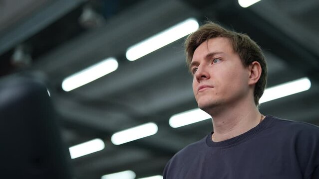 Closeup face of handsome athletic man walking on treadmill preforming warming-up run routine exercise in gym. Sporty male walking on treadmill, working on health and fitness. Shooting in slow motion.