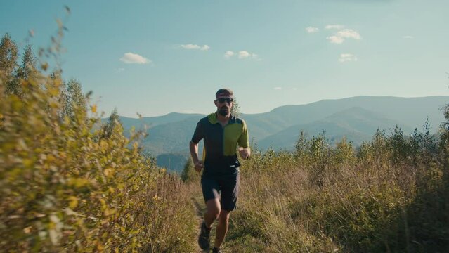 Sportive fit strong healthy Caucasian male sportsman man runner athlete jogging running mountain trail trainer run morning endurance cardio workout sport climb hiking outdoors mountainside hill nature