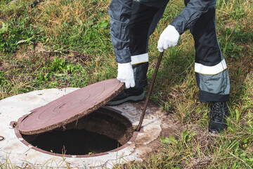 On a septic sewer well, a worker opens the manhole cover. Plumbing work