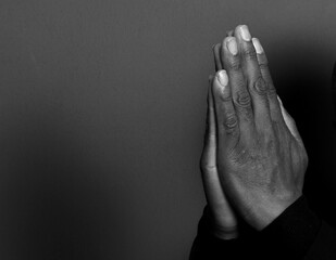 man praying to god with hands together on dark background stock photo	
