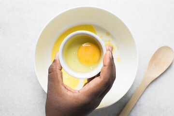 Overhead view of raw egg in a ceramic ramekin, whole raw egg in a white ramekin