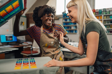 Interracial print shop workers laughing and silkscreen printing at shop