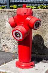 Fototapeta na wymiar Fire hydrant in french street. Red triple fire hydrant on the street, close up profil.
