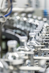 Fototapeta premium Bottles of water are being filled in a factory. The bottles are clear and have white tops