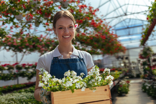 Smiling woman holding crate of flowers