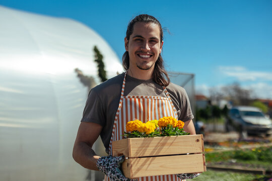 Smiling man holding wooden box of flowers