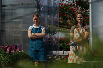 Smiling gardeners with arms crossed in greenhouse